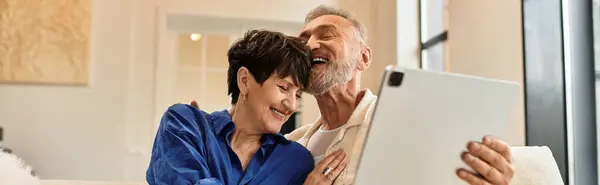 A happy couple shares joyful moments in their bright living room, smiling and laughing, banner — Stock Photo