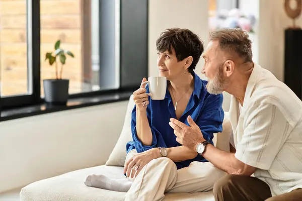 Middle-aged couple enjoys coffee and laughter at home in a cozy setting. — Stock Photo