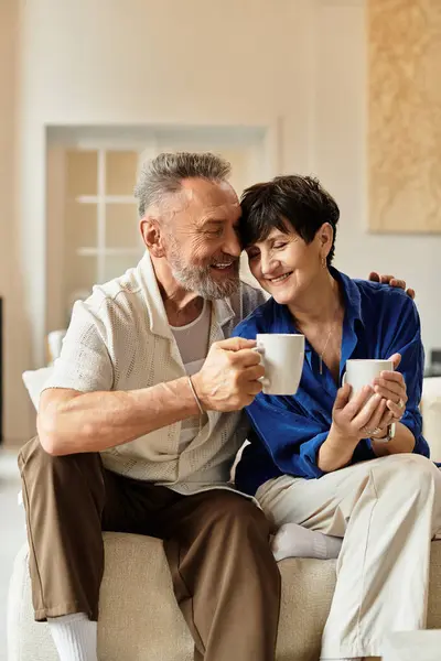 Gioioso marito e moglie condividono il caffè, abbracciando il calore e l'amore nel loro ambiente accogliente casa. — Foto stock