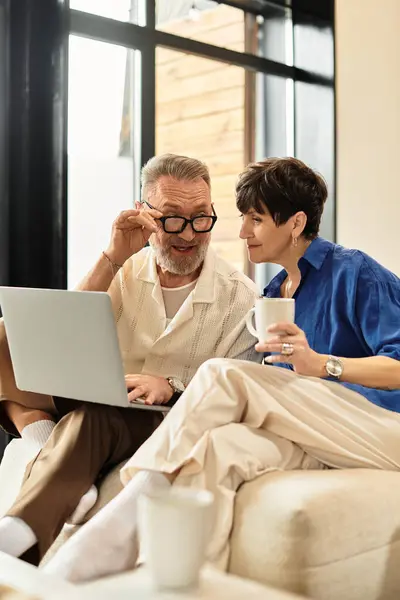 Middle aged couple shares smiles and laughter while enjoying coffee at their cozy home. — Stock Photo