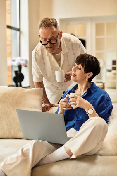 Middle aged couple enjoys quality time at home, collaborating and sipping drinks while working. — Stock Photo