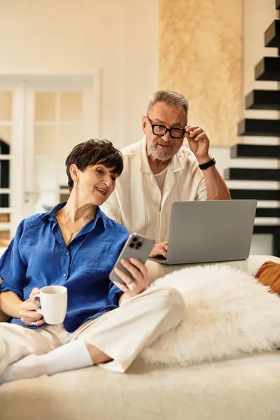A married couple relaxes at home, engaging with their devices while enjoying each other's company. — Stock Photo