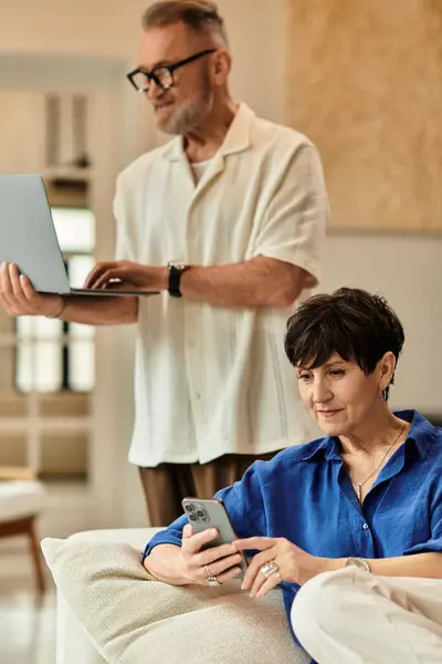 A joyful couple shares quality time at home, engaging with their devices while relaxed. — Stock Photo