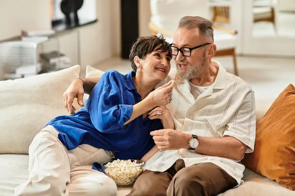 A joyful married couple enjoys each other's company at home while sharing popcorn and laughter. — Stock Photo