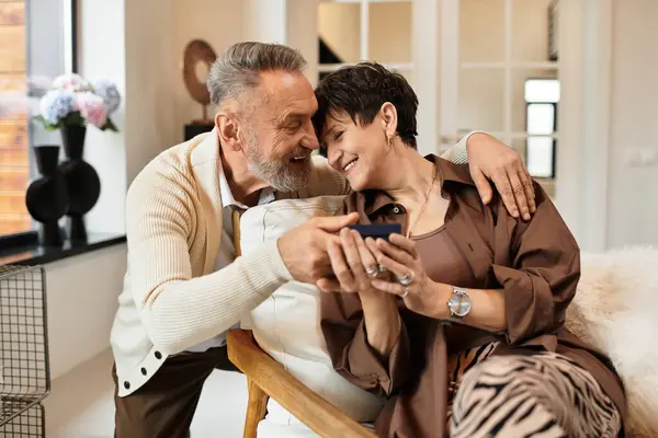 Middle aged husband and wife share a joyful moment while looking at their phone together. — Stock Photo