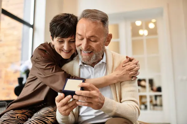 A married couple joyfully celebrates a special moment together at home, smiling and embracing. — Stock Photo