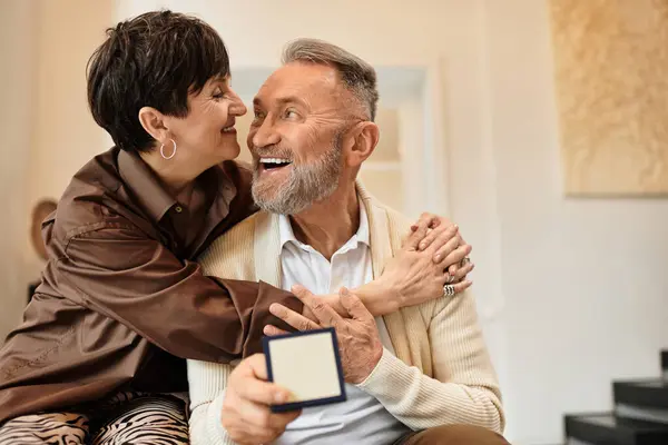 A happy couple embraces each other warmly while celebrating together in their cozy home. — Stock Photo