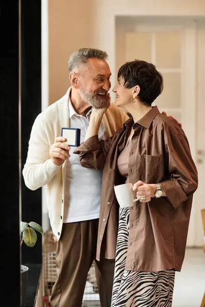 A happy couple enjoys time together at home with a cup and small gift. — Stock Photo