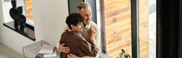 A middle-aged couple shares joy as they embrace in their warm, inviting living space, banner — Stock Photo