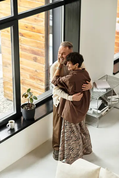 Un couple d'âge moyen partage une étreinte joyeuse à la maison, profitant de leur temps ensemble. — Photo de stock