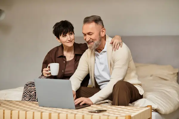Middle aged couple smiles as they collaborate on a project in their cozy living room. — Stock Photo