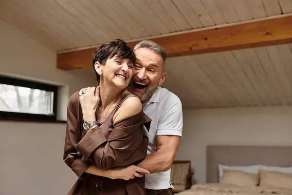 A couple embraces happily, enjoying their time together in a warm and inviting home atmosphere. — Stock Photo