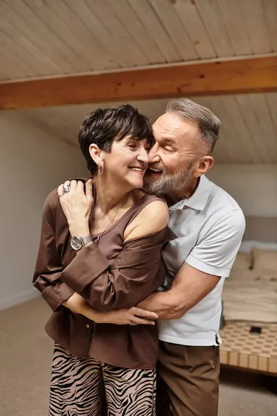 A middle aged husband and wife happily embrace, filling their home with love and laughter. — Stock Photo