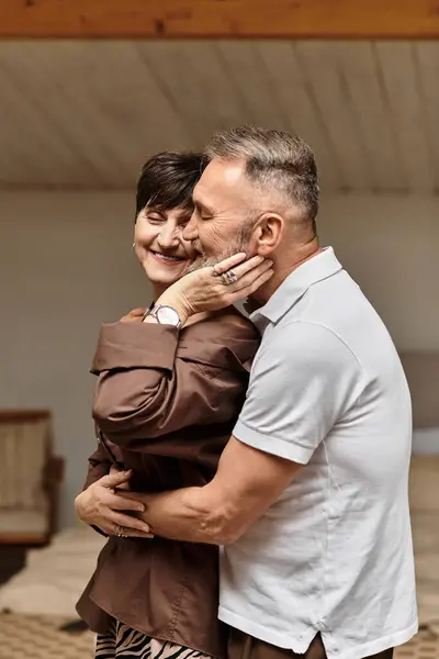 A happy middle aged couple shares a tender embrace at home, radiating love and joy together. — Stock Photo