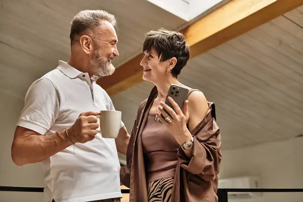 A happy middle-aged couple shares a warm drink together at home. — Stock Photo