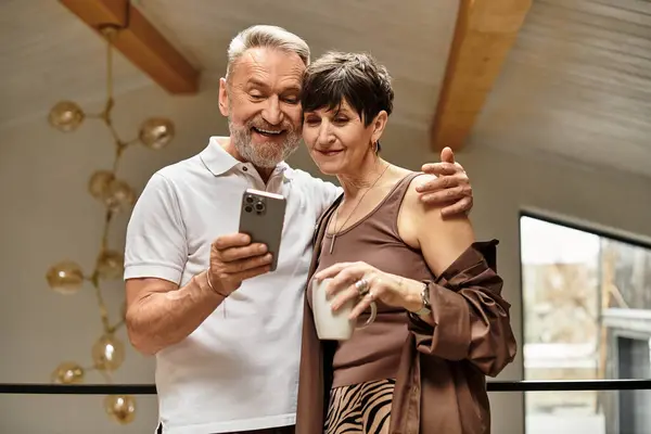 Um casal gosta da companhia um do outro, sorrindo e olhando para um smartphone juntos enquanto relaxa. — Fotografia de Stock