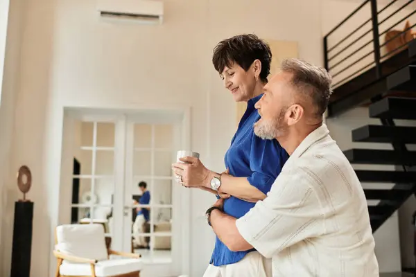 Middle aged couple enjoying time together, sharing smiles and warmth in their welcoming home. — Stock Photo