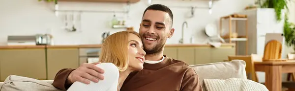 Pareja se sienta juntos en un cómodo sofá, compartiendo sonrisas y momentos tiernos en su casa. - foto de stock