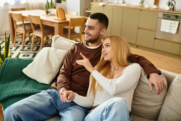 A cheerful couple sits on the sofa, sharing laughter and warmth while enjoying each others company. — Stock Photo
