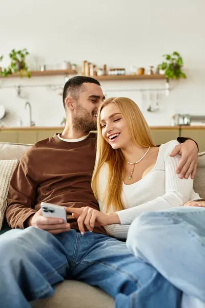 Couple cuddles on the couch, sharing laughter in their cozy afternoon living space. — Stock Photo
