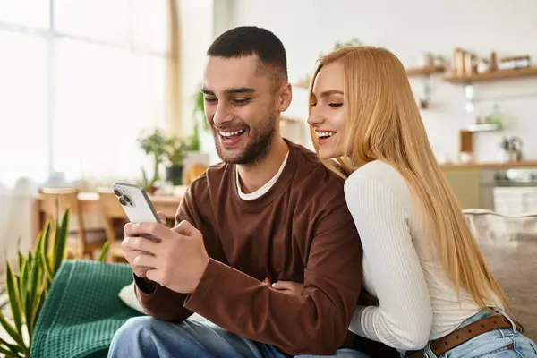 Una coppia amorevole si gode reciprocamente compagnia a casa durante la navigazione su uno smartphone, condividendo sorrisi. — Foto stock