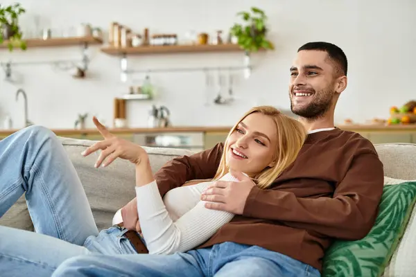 Coppia ride insieme su un accogliente divano, godendosi reciprocamente calore e amore. — Foto stock