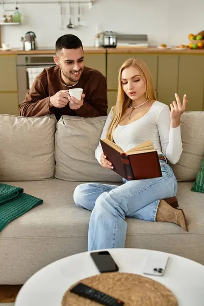 A happy couple shares their love for reading on a cozy couch in a bright living room. — Stock Photo