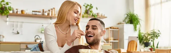 Couple shares laughter and snacks at home, enjoying quality time together in warmth. — Stock Photo