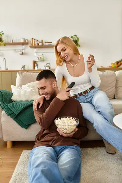 Ein Paar genießt die Gesellschaft des anderen und teilt Lachen und Snacks in seinem gemütlichen Wohnzimmer. — Stockfoto