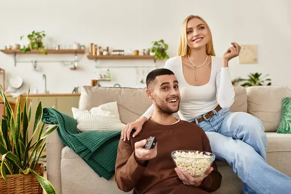 A couple enjoys a cozy movie night at home, sharing joy and snacks together. — Stock Photo
