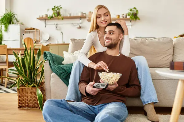 Couple relaxes in their cozy living room, sharing smiles and popcorn. — Stock Photo