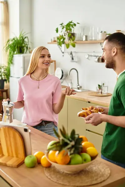 A couple enjoys sweet conversation while preparing breakfast together in a bright kitchen. — Stock Photo