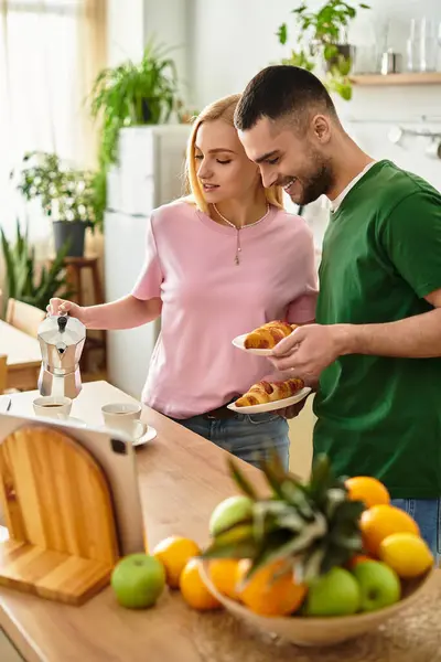 A couple shares a joyful morning at home, preparing croissants and coffee in a vibrant kitchen. — Stock Photo