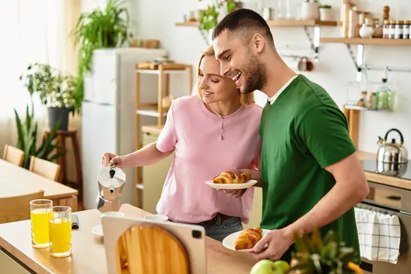 A happy couple shares a joyful breakfast moment together while preparing fresh food and drinks. — Stock Photo