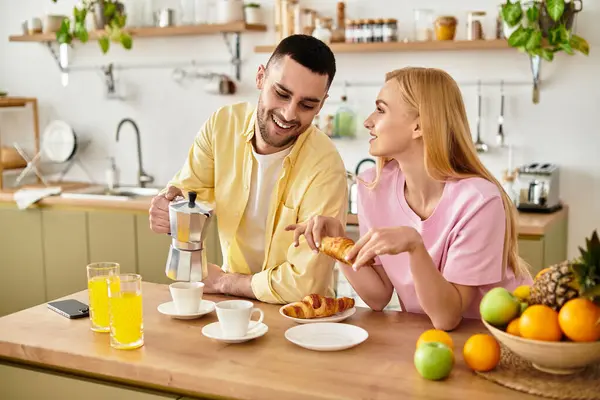 Loving couple shares joyful moments over breakfast, savoring pastries and drinks in their kitchen. — Stock Photo