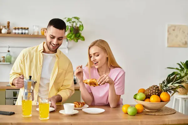 A couple shares a joyful breakfast, enjoying pastries and drinks while smiling. — Stock Photo