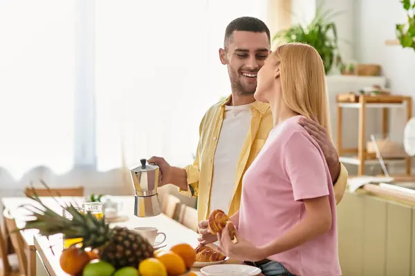 Утренний свет наполняет теплую кухню, так как пара делится смехом, кофе и выпечкой вместе. — стоковое фото