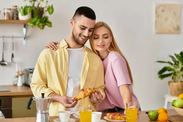 Couple shares a delightful moment in their cozy kitchen while relishing breakfast pastries. — Stock Photo