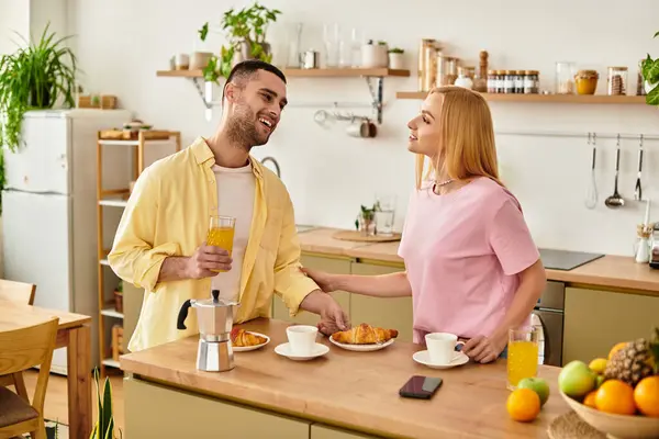 Loving couple shares laughter and breakfast together in their warmly decorated kitchen setting. — Stock Photo
