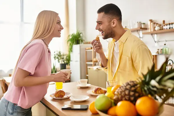 A joyful moment where a man and woman share breakfast, exchanging warm smiles and food. — Stock Photo
