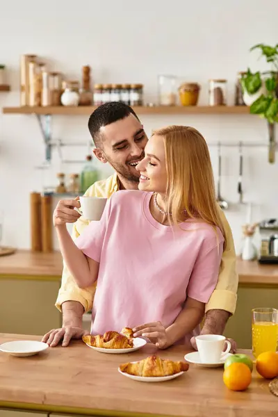 A couple enjoys a delightful breakfast experience in their cozy kitchen, embracing love and warmth. — Stock Photo