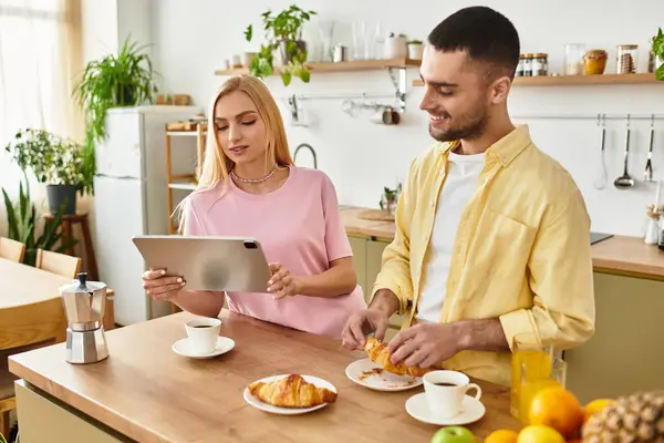 Una pareja disfruta de un delicioso desayuno mientras comparten sonrisas y risas mientras preparan comida. - foto de stock