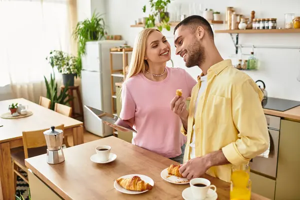 Paar frühstückt zusammen in einer gemütlichen Küche und teilt Lächeln und leckere Croissants. — Stockfoto