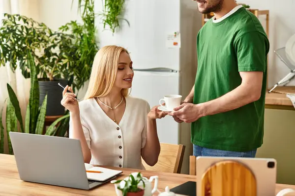 A man hands a cup to a woman, both smiling and radiating affection in their cozy home. — Stock Photo