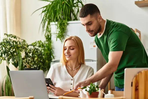 A couple shares a joyful moment at home, collaborating on a project with laptops and smiles. — Stock Photo