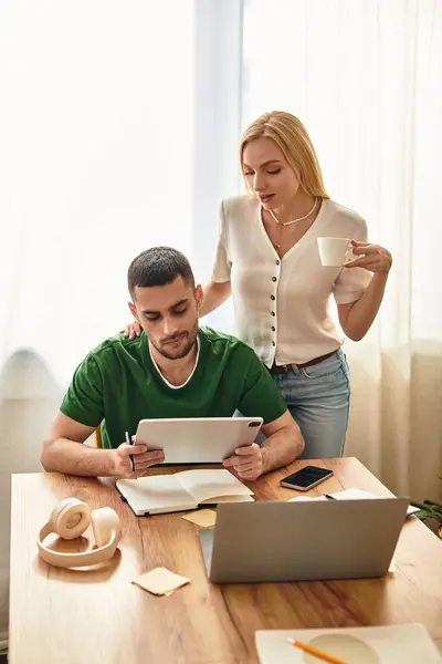 Engaged couple shares a cozy moment at home, with one studying and the other supporting. — Stock Photo