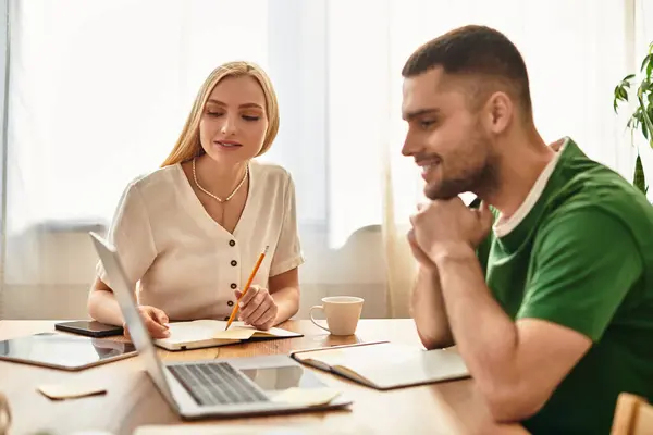 Ein Paar arbeitet freudig am Esstisch zusammen, teilt Ideen und lacht. — Stockfoto