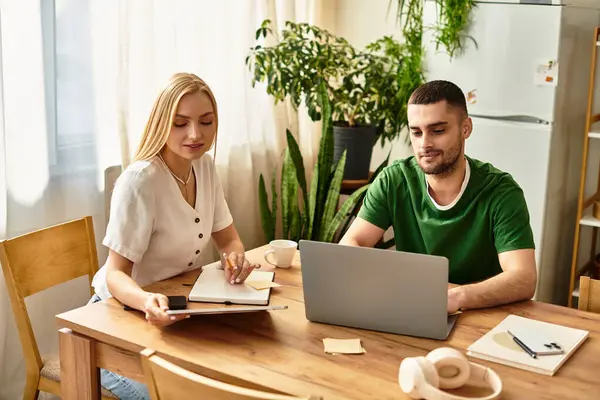 A loving couple works on tasks together at a wooden table, enjoying each others company. — Stock Photo