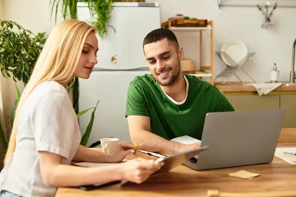 Couple shares laughter and ideas at their kitchen table amidst green plants and warm sunlight. — Stock Photo