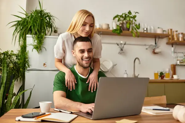 Una pareja alegre comparte un momento acogedor en su casa, conectado a través del trabajo y la risa. - foto de stock